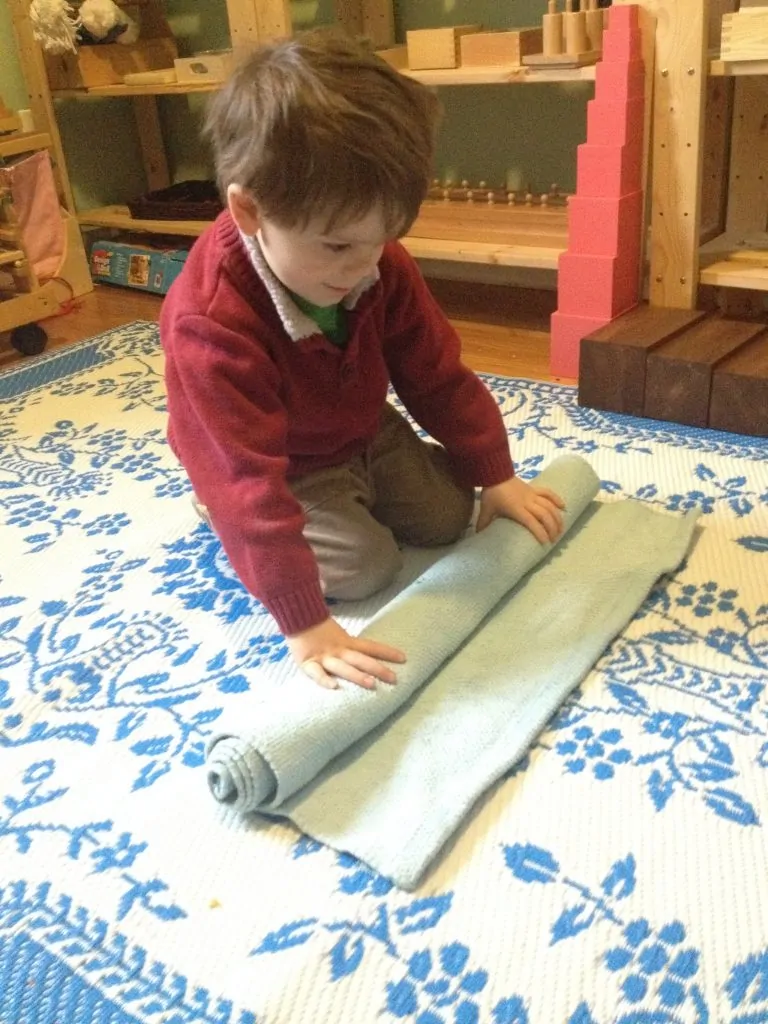 Child unrolling a work mat - Montessori presentation and lesson at Sugar, Spice and Glitter