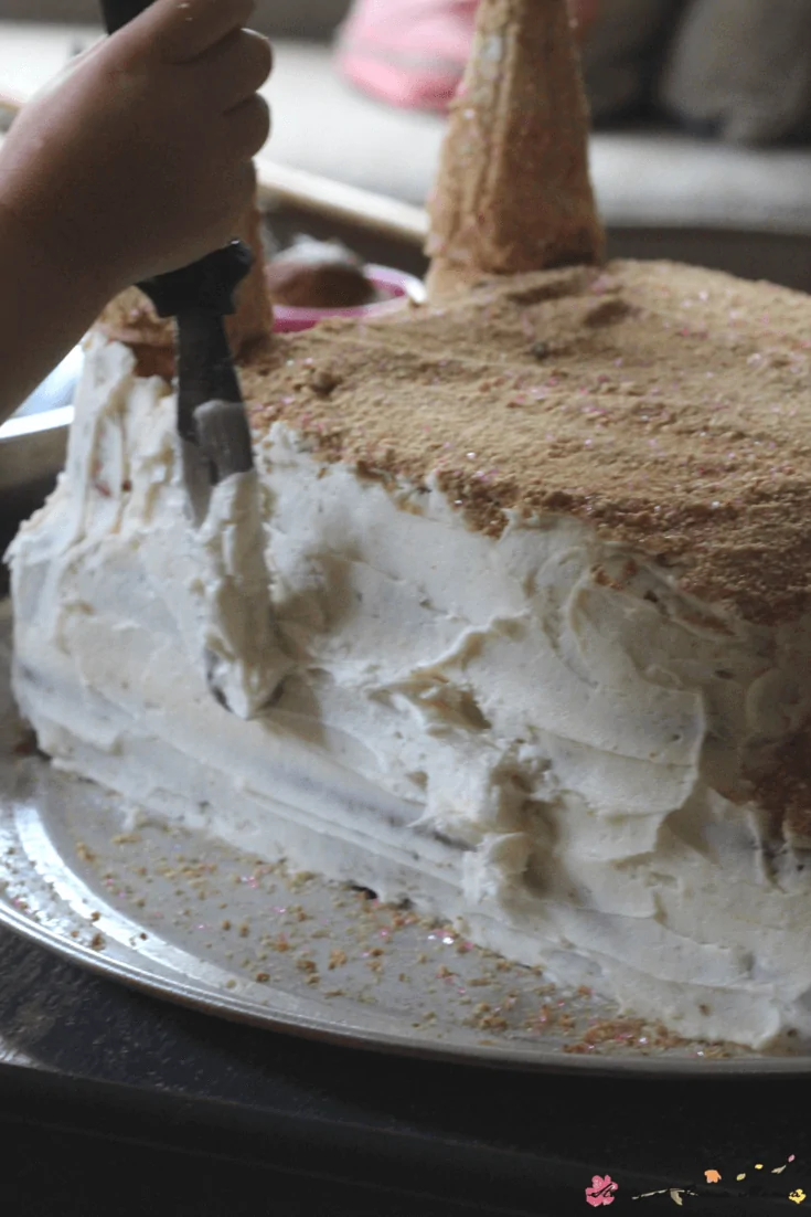 Homemade vanilla buttercream helps the edible sand stick to this homemade sandcastle cake