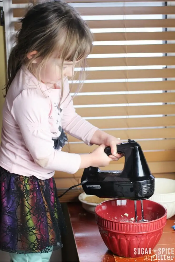 a child using a mixer in a bowl to make apple loaf