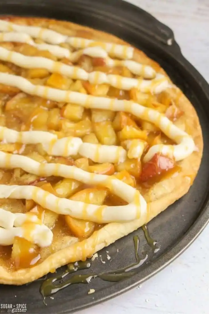 The perfect fall dessert for kids to make, this apple pie dessert pizza is easy to make with apple pie topping, cream cheese frosting and caramel drizzle