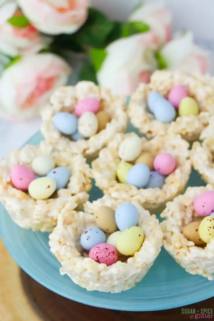 close-up picture of blue cake stand holding rice krispie treats shaped like birds nests and filled with chocolate mini eggs