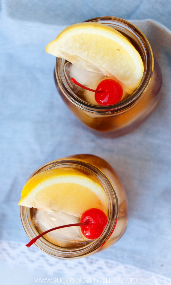overhead image of two mason jars full of Long Island Iced Tea garnished with lemon wedges and maraschino cherries
