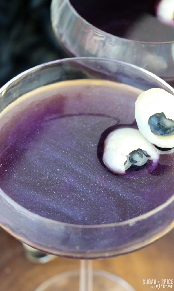 How mesmerizing is this shimmery night sky rum cocktail - a pretty and delicious Halloween cocktail with fruit eyeballs - take out the garnish for a night sky cocktail that you can serve all year round