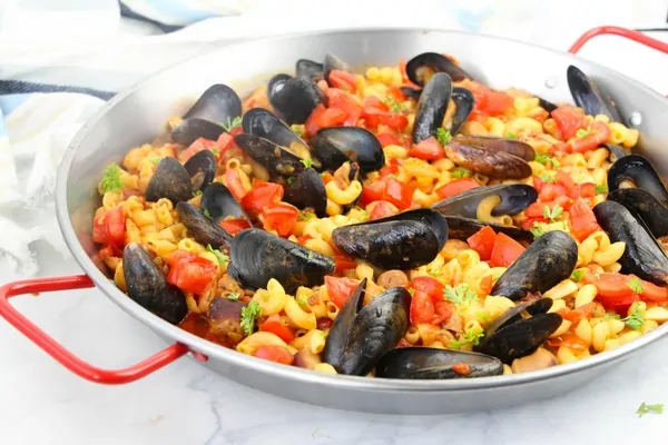 A fun twist on a classic Spanish paella, a Pasta Paella featuring fresh veggies, chicken, sausage, mussels and shrimp - and a good dose of smoked paprika!