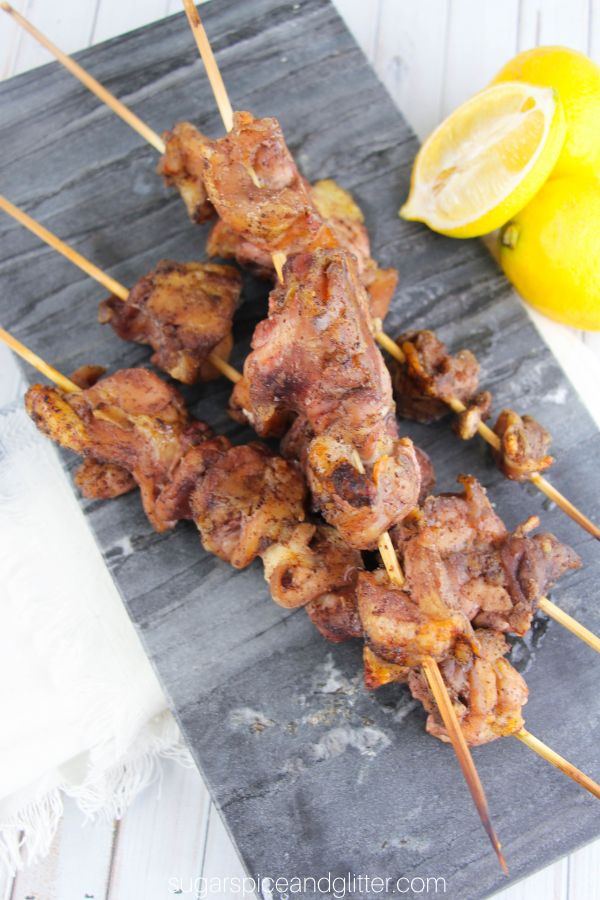 sumac chicken kebabs on a slate gray tray with lemons on the side