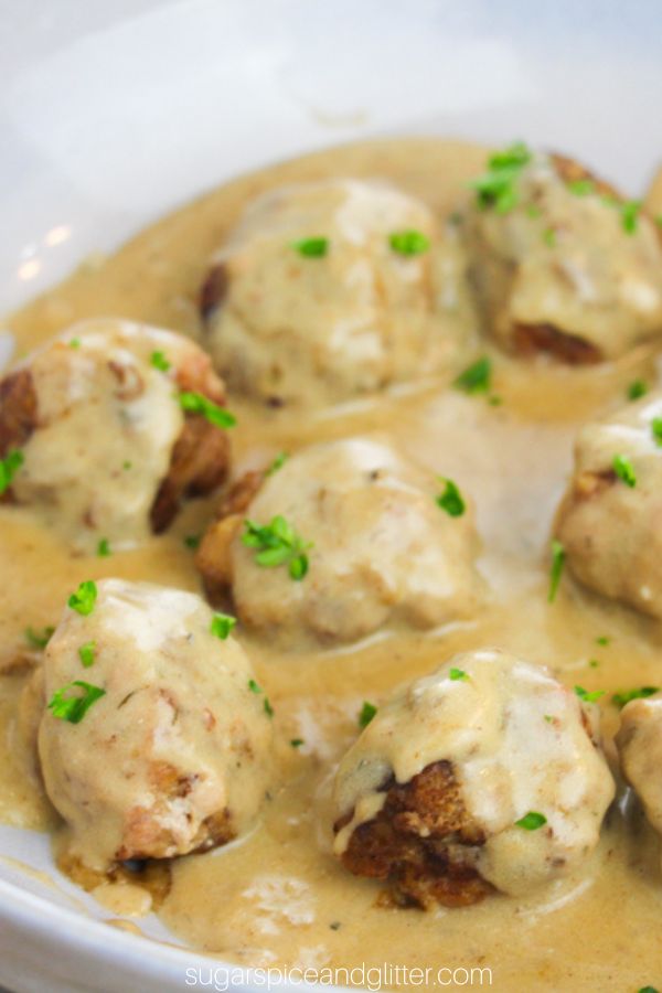 close-up image of swedish meatballs and gravy in a blue bowl sprinkled with parsley
