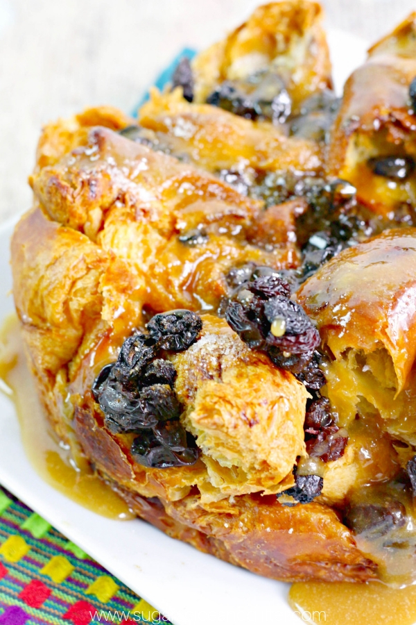 a white platter filled with raisin bread pudding dripping with Bailey's butter sauce