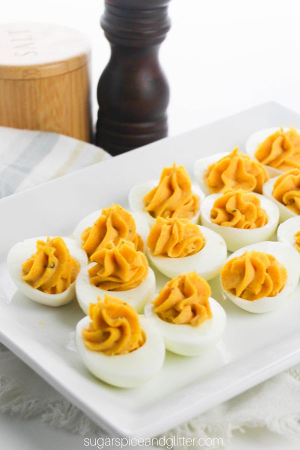 deviled eggs on a white platter with salt and pepper shakers in the background
