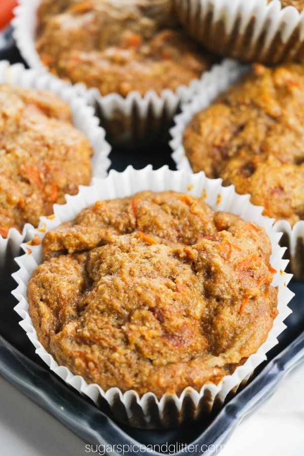 close-up of a carrot muffin in a white muffin liner nestled in the corner of a blue ceramic tray