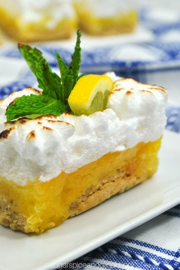 close-up picture of a slice of lemon meringue pie bar with a slice of lemon and fresh mint on top