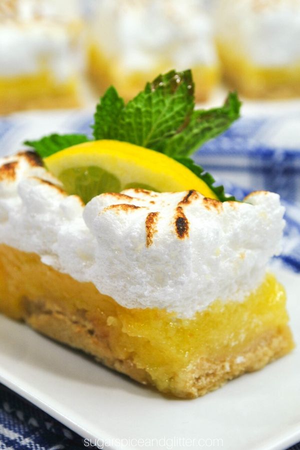 close-up picture of a slice of lemon meringue pie bar with a slice of lemon and fresh mint on top