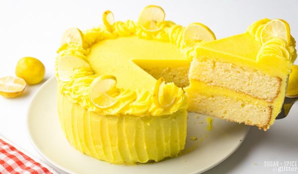 A slice of lemon cake being removed from the rest of the cake using a cake server