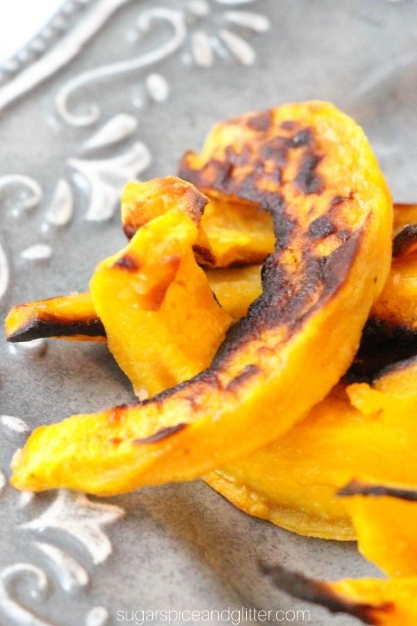 close-up image of slices of charred acorn squash fries on a gray plate
