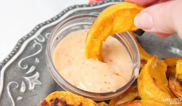 an acorn squash fry being dipped into garlic aioli