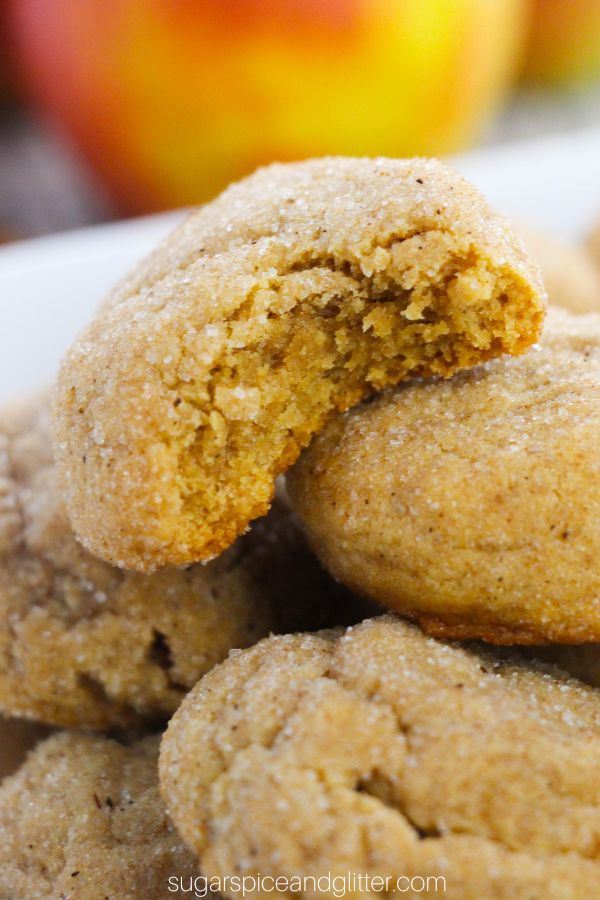 A pile of apple butter snickerdoodle cookies, with the top cookie showing a bite taken out of it