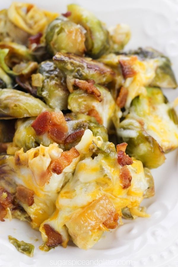 Close-up of cheese and bacon covered brussels sprouts on a white plate