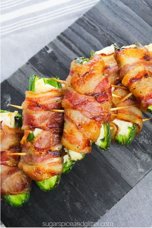 bacon-wrapped jalapeno poppers on a slate gray tray set on a gray napkin