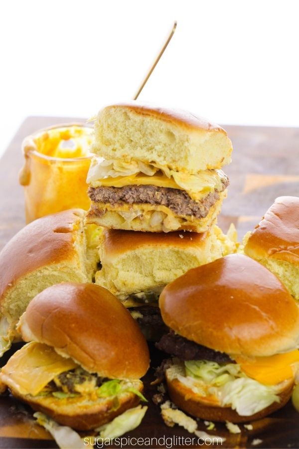 a stack of Big Mac sliders on a wooden cutting board with a jar of homemade big mac sauce in the background