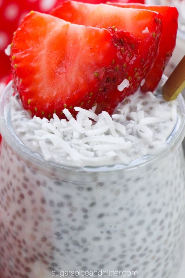 close-up picture of a glass jar filled with chia seed pudding, topped with shredded coconut and sliced strawberries