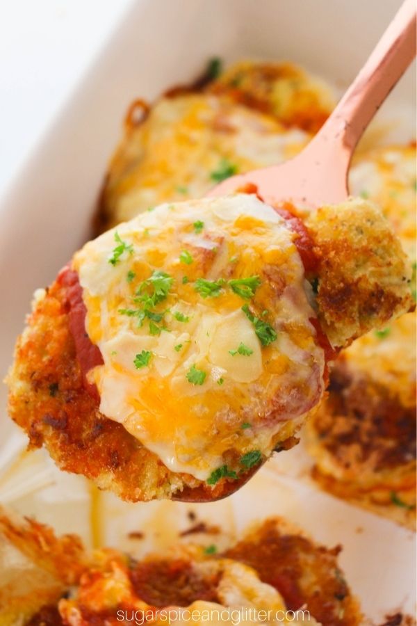 spatula lifting a baked chicken Parmesan over a casserole dish full of more chicken Parmesan