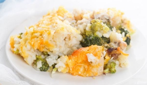 close-up image of a small white plate filled with broccoli chicken casserole topped with cheese and bread crumbs
