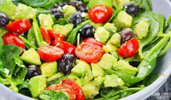 close-up of a large blue bowl full of Greek spinach salad on a gray napkin
