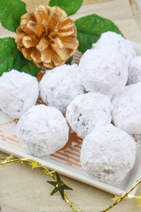 powdered sugar coated rum balls on a white plate garnished with Christmas decorations