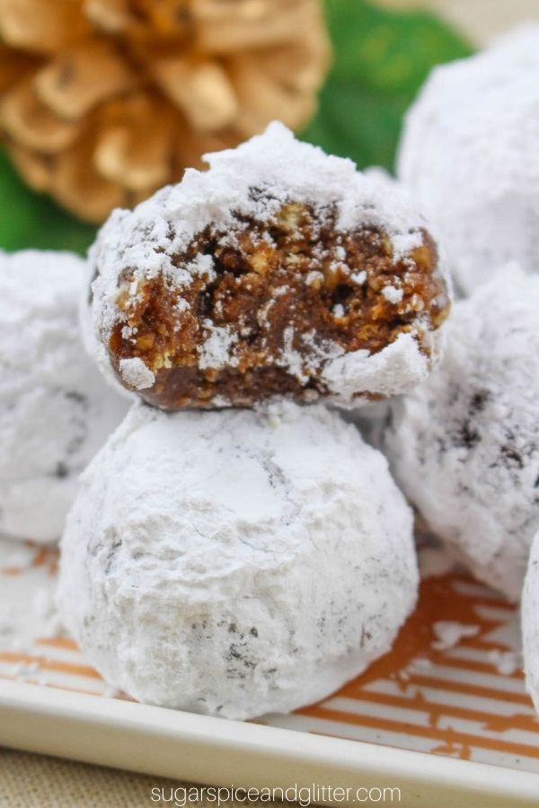 powdered sugar coated rum balls on a white plate garnished with Christmas decorations