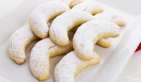 crescent cookies dusted with powdered sugar on a white platter