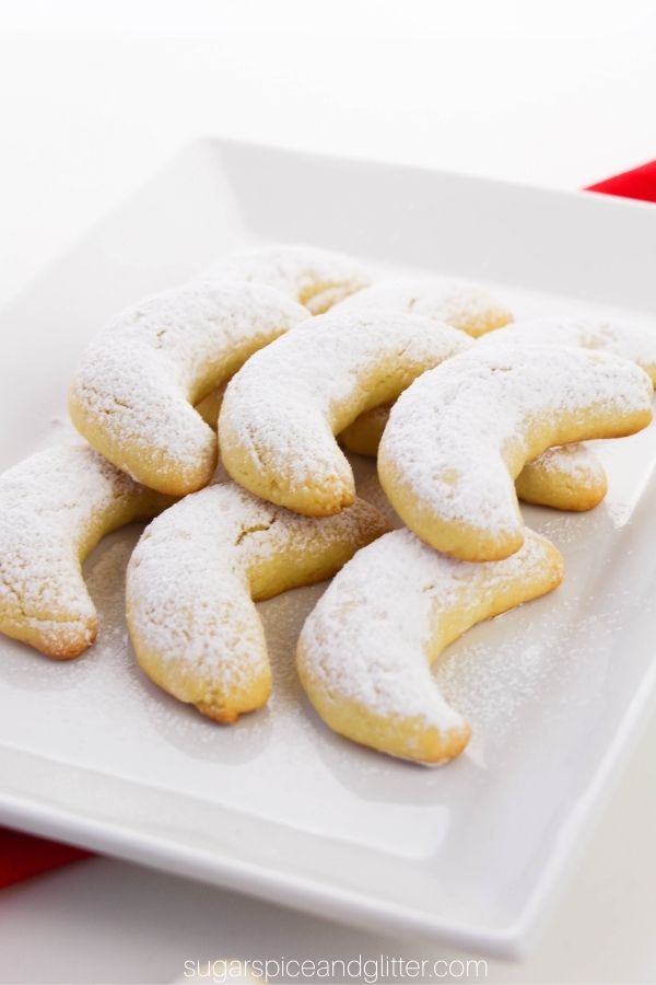 crescent cookies dusted with powdered sugar on a white platter