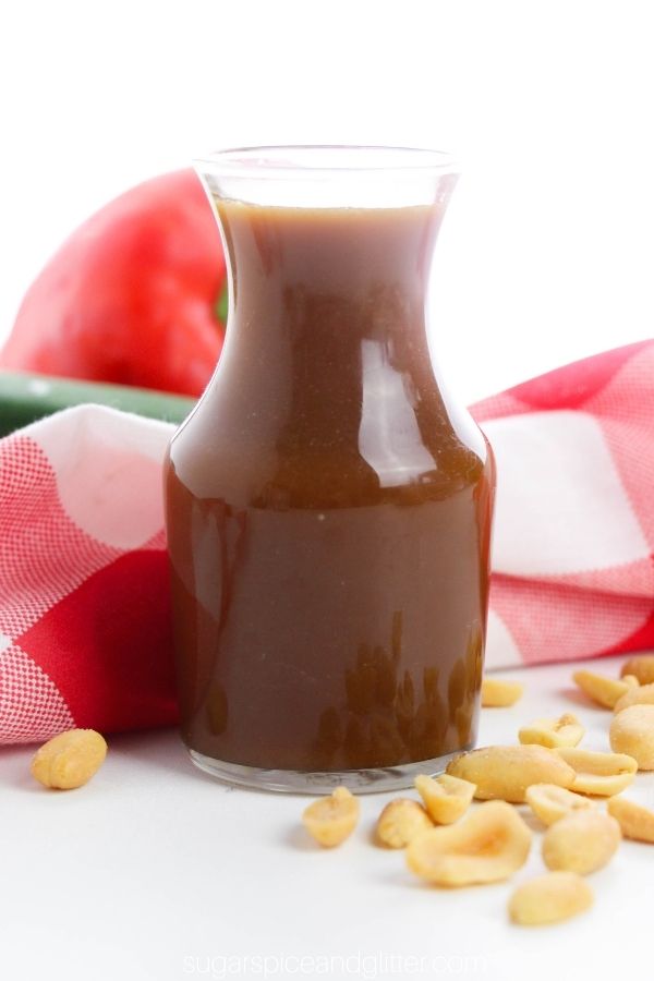 a small glass karafe filled with homemade Kung Pao sauce surrounded by a scattering of peanuts