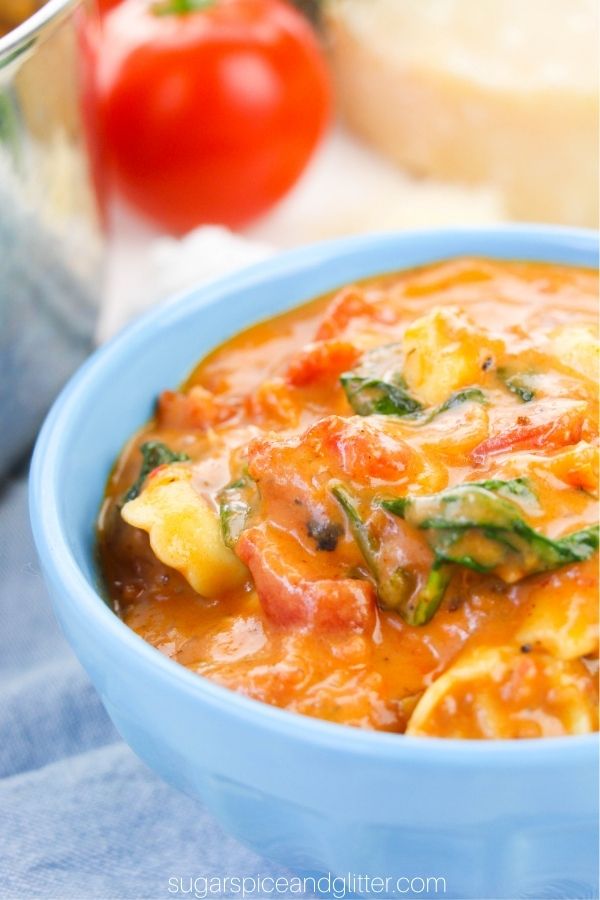 close-up image of a blue bowl filled with tomato tortellini soup