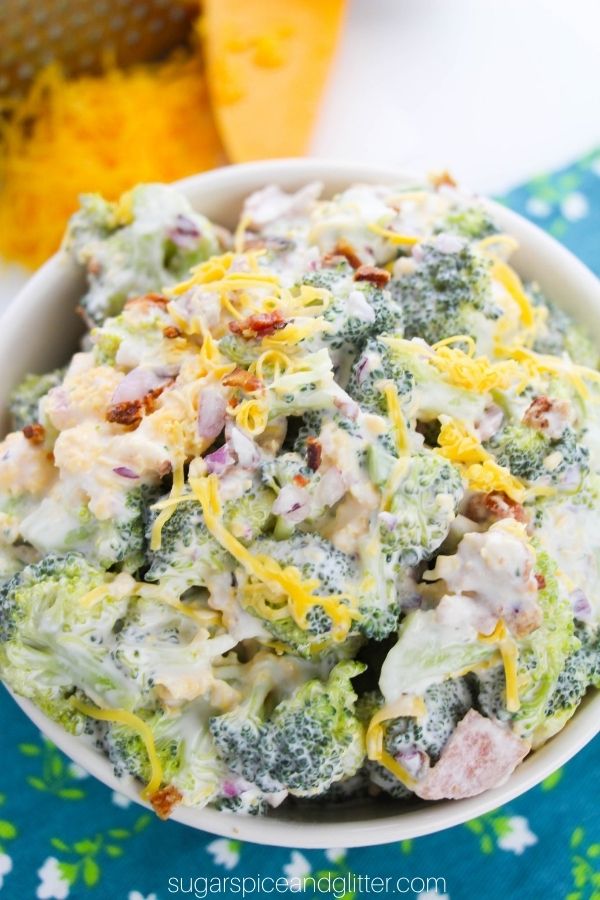 close-up of a white bowl filled with broccoli salad set on a blue floral napkin