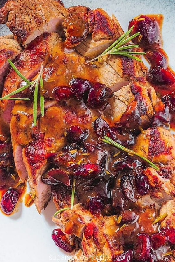 close-up image of cranberry orange pork tenderloin sprinkled with fresh rosemary