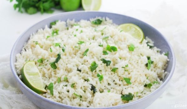 light blue bowl filled with cilantro lime rice, garnished with lime wedges