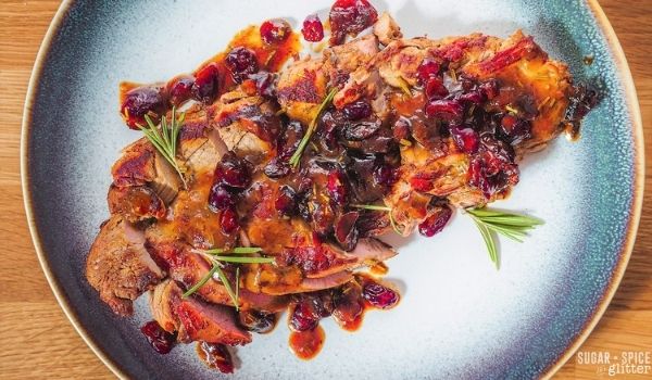 cranberry orange pork tenderloin on a blue plate on a wooden table