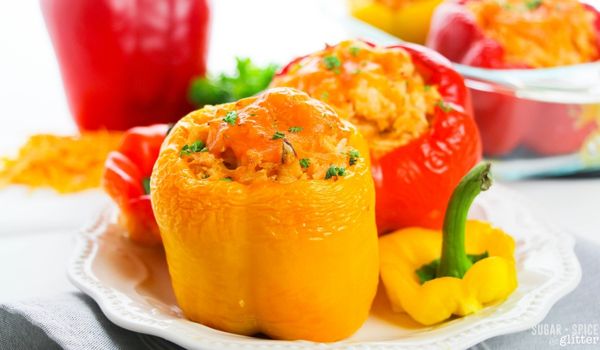 bright bell peppers stuffed with cheese, rice and buffalo chicken on a white plate
