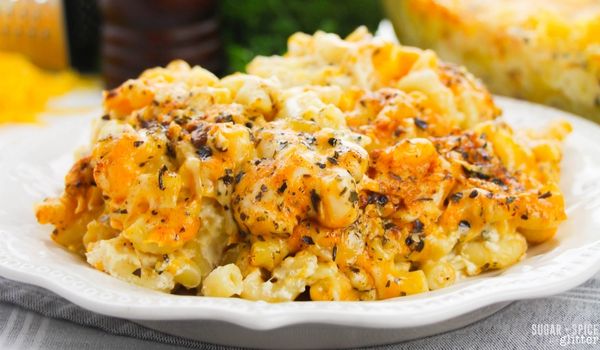 close-up image of cheesy baked mac and cheese with plenty of seasoning on top on a white plate