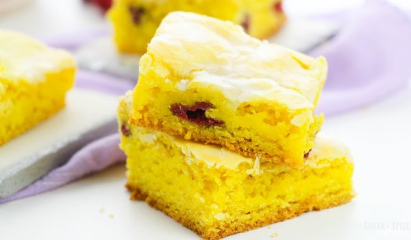 stack of lemon raspberry blondies in front of a lilac napkin
