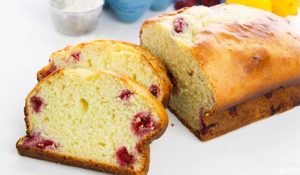 a lemon raspberry loaf cake sliced into individual servings with the ingredients needed to make it in the background