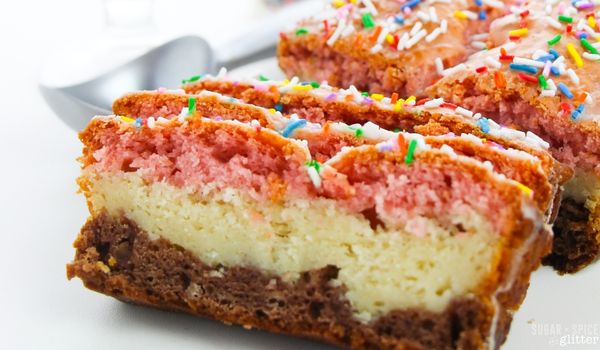 slices of Neapolitan bread on a white table showing distinct chocolate, vanilla and strawberry layers, topped with rainbow sprinkles