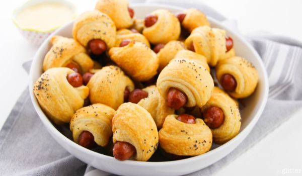 blue bowl filled with piggies in a blanket set on a gray napkin
