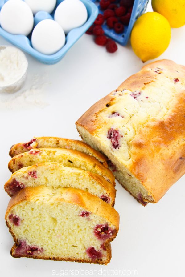 overhead image of a lemon raspberry loaf cake sliced into individual servings with the ingredients needed to make it in the background