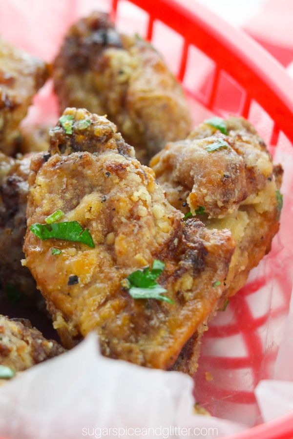 close-up image of lemon pepper chicken wings in a red BBQ basket on a red plaid napkin