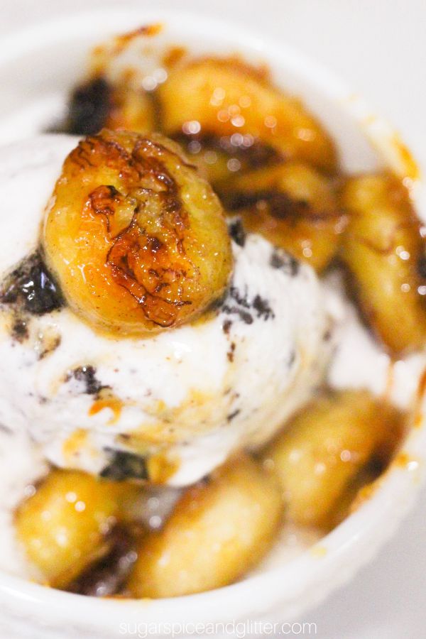 close-up picture of caramelized bananas on top of ice cream in a white pedestal bowl