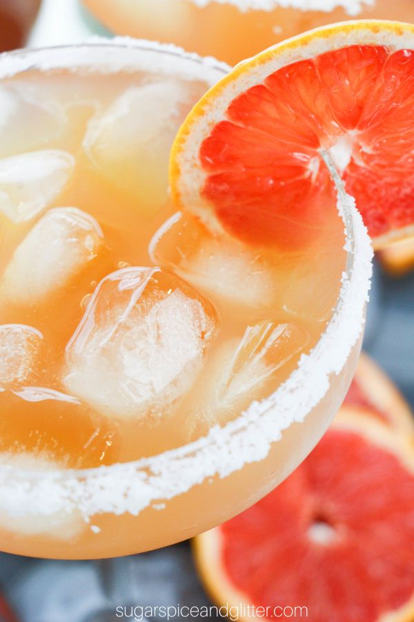 overhead close-up shot of a margarita glass rimmed with salt, garnished with a grapefruit slice and filled with ice and grapefruit margarita
