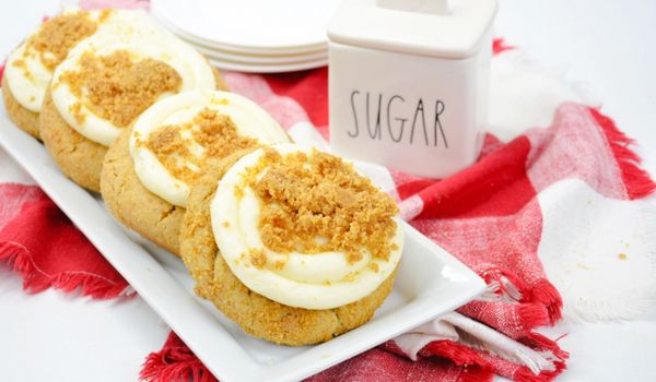 cheesecake cookies in a row on a white platter set on a red plaid napkin