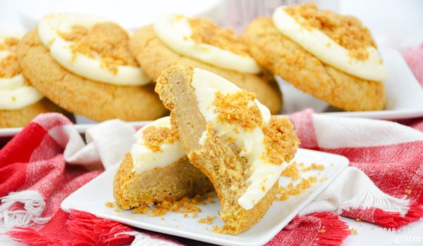 a thick cheesecake cookie broken in half on a white square plate, with more cookies on a white platter in the background