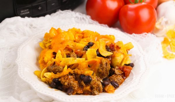 a white plate full of frito pie in front of a crockpot