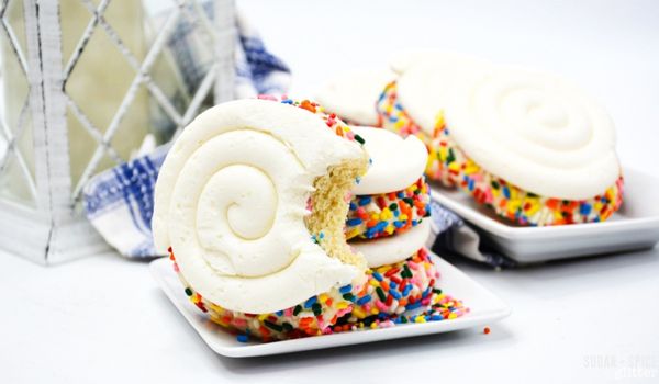 a milkshake cookie with a bite taken out on a white square plate in front of a stack of more cookies